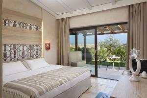 a bedroom with a bed and a sliding glass door at Baglioni Resort Sardinia - The Leading Hotels of the World in San Teodoro