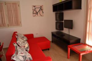 ein Wohnzimmer mit einem roten Sofa und einem TV in der Unterkunft CASA NORI - Apartamento a 4 minutos de la playa in Tías