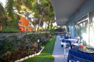 a patio with tables and chairs and a garden at Aurea Hotel in Tortoreto Lido