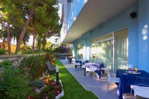 un patio con tavoli e sedie e un edificio blu di Aurea Hotel a Tortoreto