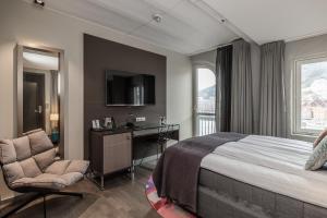 a bedroom with a bed and a desk and a window at Clarion Hotel Admiral in Bergen