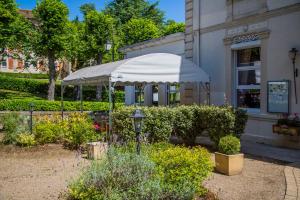 a white umbrella in a garden in front of a building at Hôtel des Thermes in Bourbon-lʼArchambault