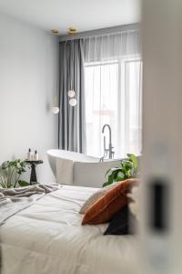 a white bathroom with a tub and a bed at Choya Apartments in Poznań