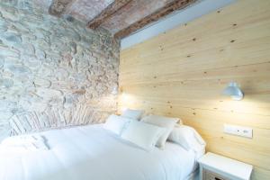 Bett in einem Zimmer mit einer Steinmauer in der Unterkunft Bruma Boutique Apartment in Girona