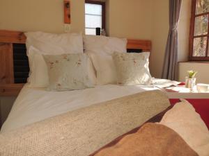 a large bed with white sheets and pillows at Stone Haven at Nieu Bethesda in Nieu-Bethesda