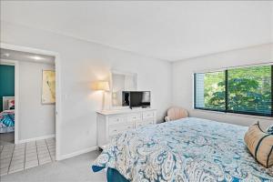 een slaapkamer met een bed, een tv en een raam bij Sea Oats 241 Apartment in Boca Grande