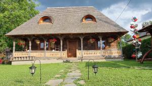 a small house with a porch and two windows at Casa din Susani in Călineşti