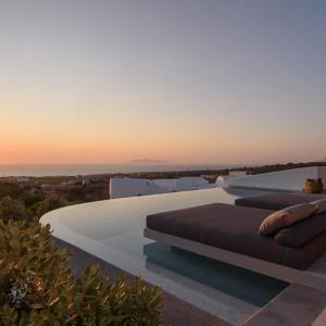 a pool with two couches on the side of a house at Este Luxury Suites in Fira