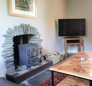 sala de estar con chimenea de piedra y TV en Wellstone Cottages - Jasmine en Llanfyrnach