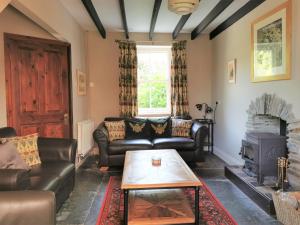 a living room with leather furniture and a fireplace at Wellstone Cottages - Jasmine in Llanfyrnach