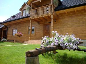 a wooden house with a bunch of flowers on a fence at Agroturystyka Paradiso in Ropa