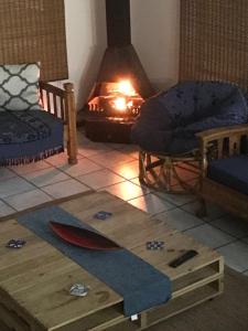 a living room with a surfboard on the floor and a fireplace at Jbay Tides in Jeffreys Bay +21 photos