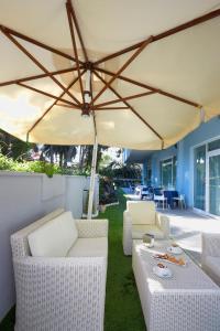 a patio with white chairs and an umbrella at Aurea Hotel in Tortoreto Lido