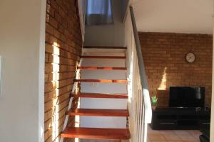 a wooden staircase in a room with a brick wall at Warm, Comfy Duplex 5min Walk To North Park Mall in Pretoria
