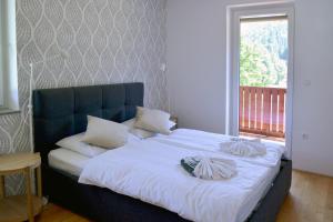 um quarto com uma cama grande com lençóis brancos e almofadas em Villa Planina em Kranjska Gora