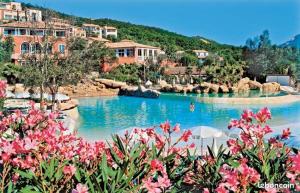 - une piscine dans un complexe avec des fleurs roses dans l'établissement les Restanques Du Golf de Saint Tropez, 83310 Grimaud, France Appartement, à Grimaud