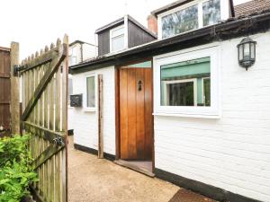 uma casa branca com uma porta de madeira e uma cerca em Apple Tree Cottage em Lincoln