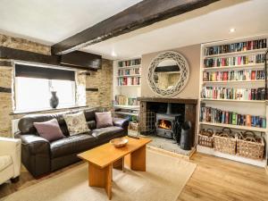 a living room with a leather couch and a fireplace at Apple Tree Cottage in Lincoln