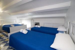 a room with two blue beds with white pillows at CASSIODORO SUITE B&B in Marina di Davoli