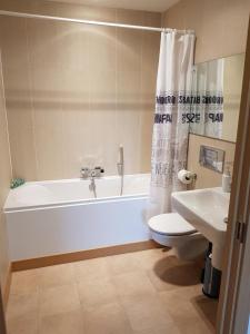 a bathroom with a tub and a toilet and a sink at Vetrelax Basildon Blake Apartment in Basildon