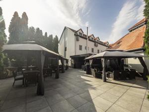 a patio with tables and umbrellas in front of a building at Club Hotel Pegasus in Tiszaug