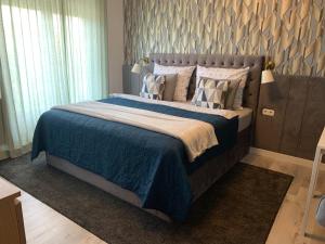 1 dormitorio con 1 cama con manta azul y almohadas en Hollik Apartmanház, en Balatonfüred