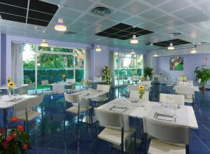a dining room with white tables and white chairs at Aurea Hotel in Tortoreto Lido