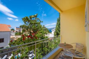 einen Balkon mit einem Tisch, Stühlen und einem Baum in der Unterkunft Castelletto in Cavtat