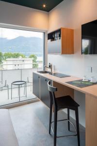 cocina con encimera y mesa con taburete en Riva Rooms & Studios - Check-In 24hr, en Locarno