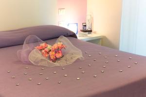 a bouquet of flowers sitting on top of a bed at Aurea Hotel in Tortoreto Lido
