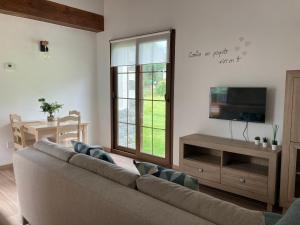 ein Wohnzimmer mit einem Sofa und einem Flachbild-TV in der Unterkunft Apartamentos La Presa El Molin in Cangas de Onís