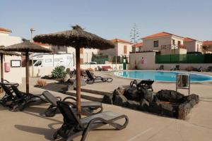 a pool with chairs and umbrellas in a yard at Fuertedreams in La Oliva