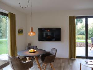 a dining room with a table and chairs and a tv at Ferienwohnungen Seerose in Bad Zwischenahn