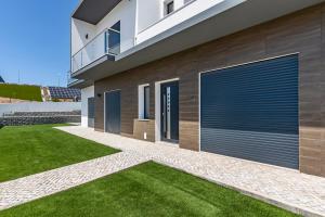 une maison avec des portes de garage bleues sur le côté dans l'établissement 4 Bed Villa - Sleeps 8 - Pool - Garden - Parking, à Torre