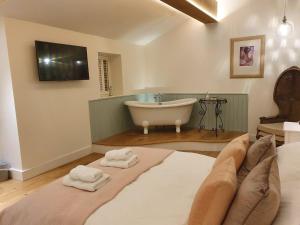 a bedroom with a tub and a bed with towels at Twitchers Cottage in Kendal