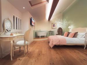 a bedroom with a bed and a desk and a tub at Twitchers Cottage in Kendal +15 photos