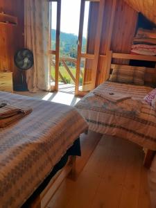 2 Betten in einem Zimmer mit einem großen Fenster in der Unterkunft Pousada Canever in Lauro Müller
