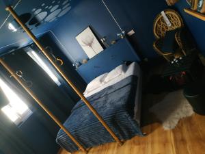 een bed in een blauwe kamer met een paal bij Suite 50 Nuances avec Balnéothérapie pour 2 in Caen
