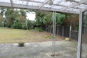 a patio with a pergola and a yard at Brookside Lodge in Baldock