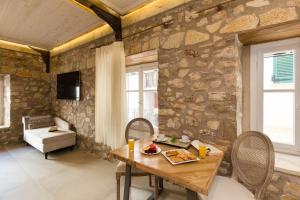 a dining room with a wooden table and a stone wall at Stone Suites at Lefkada's Old Port in Lefkada