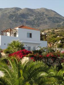 a white house with flowers in front of a mountain at Villa Karin , with beautiful seaview! in Georgioupoli