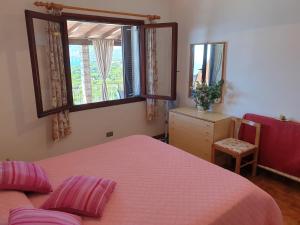 1 dormitorio con cama rosa y ventana en Appartamenti Il Sogno, en Capoliveri