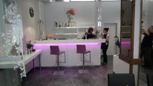 a woman standing at a bar with purple bar stools at Hôtel des Pays Bas in Lourdes