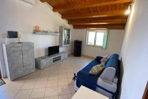 een woonkamer met een blauwe bank en een tv bij Loft incantevole con idromassaggio esterno privato in Patti