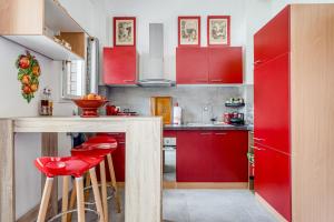 una cocina roja con armarios rojos y taburetes rojos en Le Parc, en Carpentras