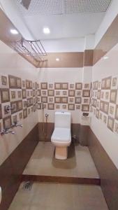 a bathroom with a toilet and pictures on the wall at Railview Residency in Alleppey +16 photos