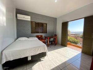 ein Schlafzimmer mit Bett, Tisch und Balkon in der Unterkunft Império Hotel in Caçu