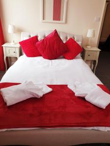 Cama con sábanas y almohadas rojas y blancas en Preston Hotel, en Yeovil