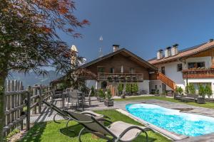 a house with a swimming pool and chairs in the yard at Residence Alpenrose in Bressanone