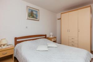 a bedroom with a white bed with a dresser and a cabinet at Guest House Vulić in Dubrovnik